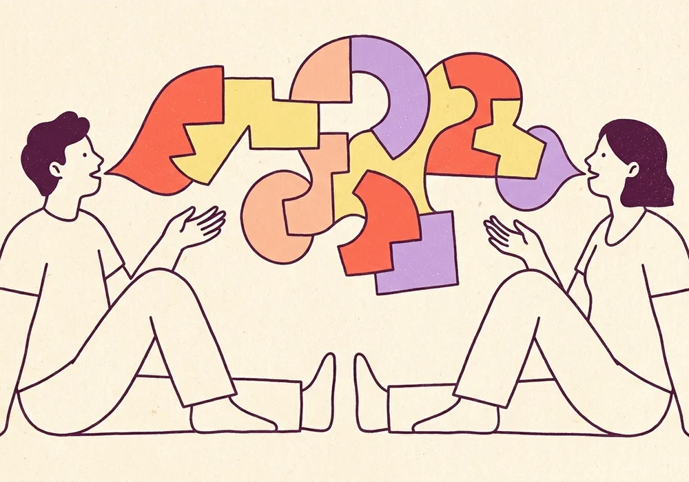 Two people fitting colorful speech-bubble puzzle pieces together